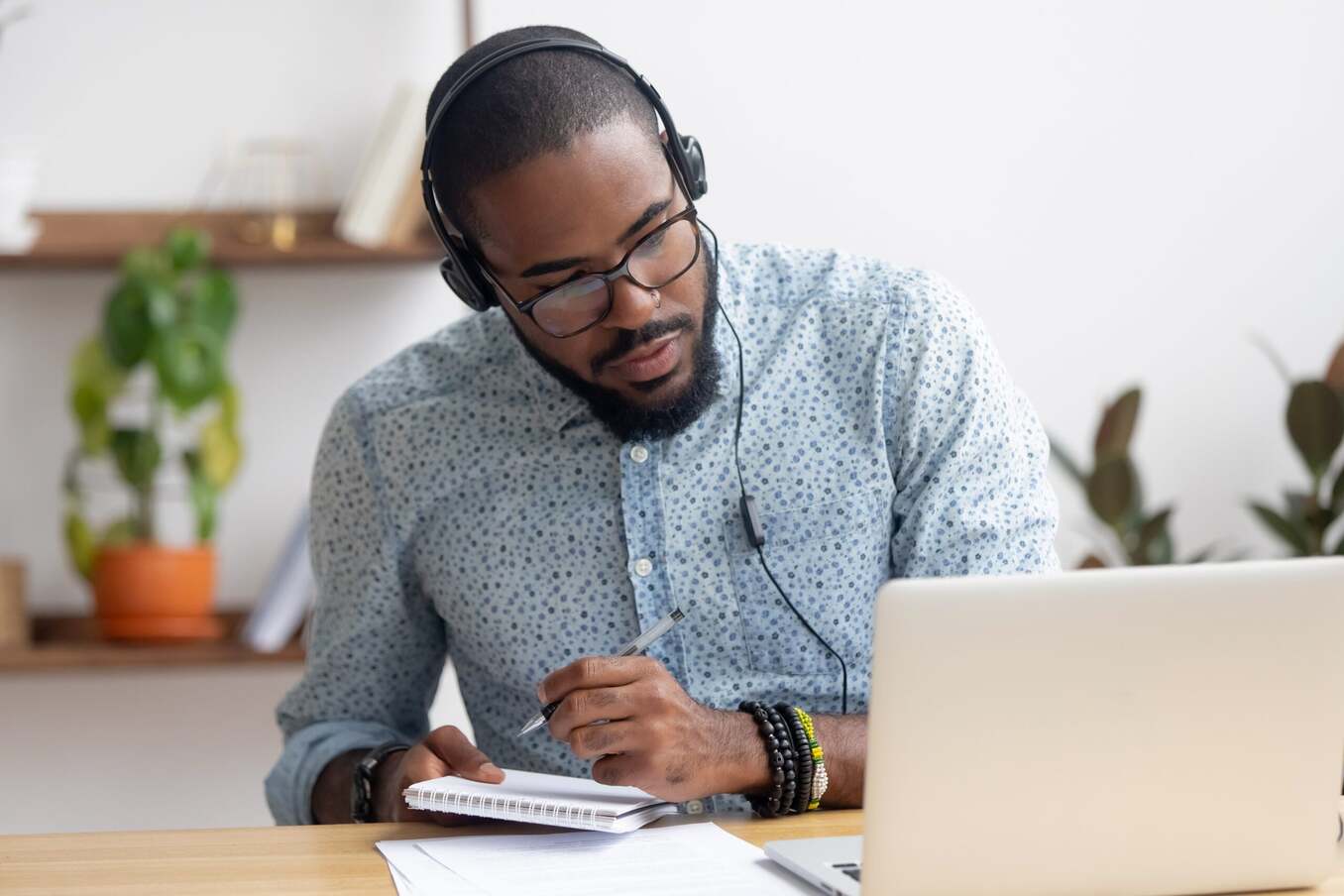 A man focused on his laptop while taking notes