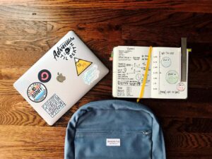 Backpack and laptop sit on a wood table.