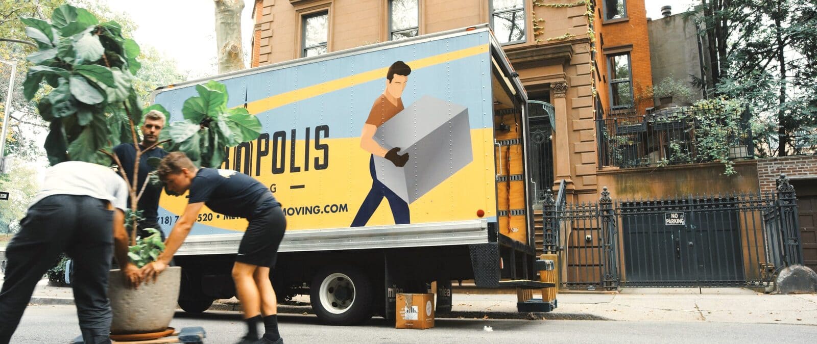 Movers load boxes and a potted plant into a moving van