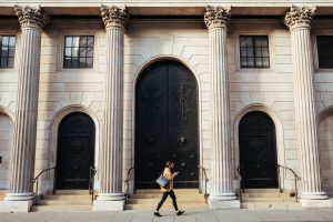 Woman walks in front of a bank entrance.