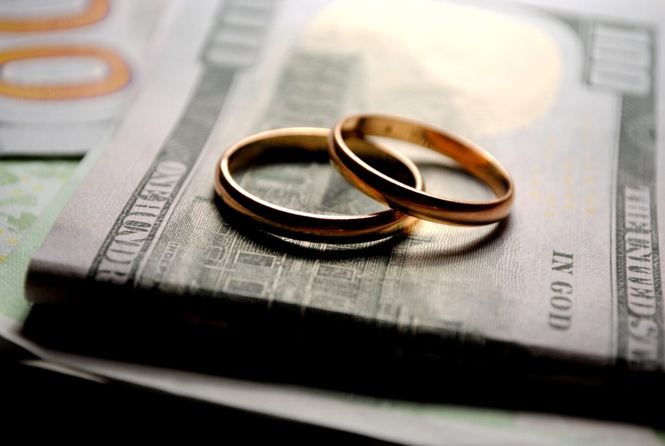 Wedding rings on top of a stack of dollars