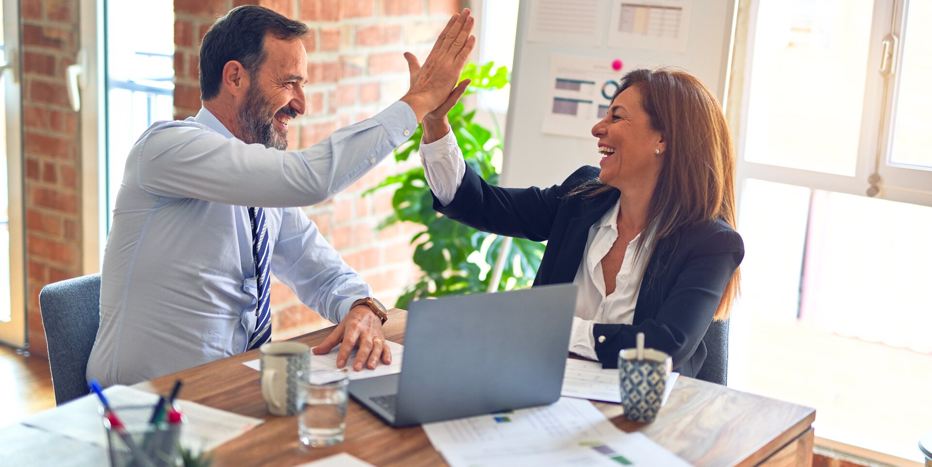 Coworkers highfiving in an office environment