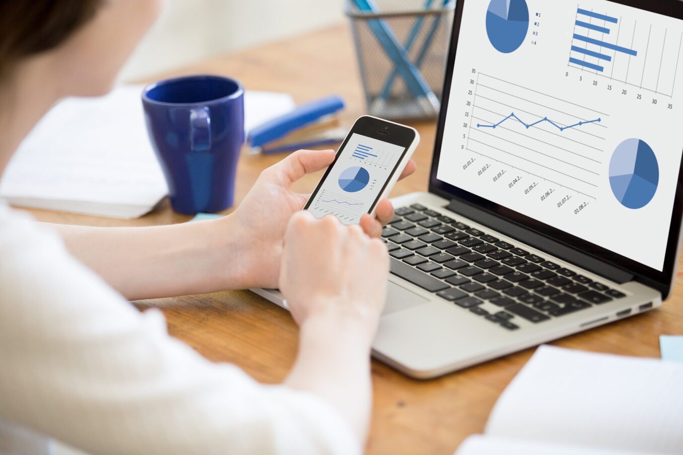 Person reviewing charts on their phone and laptop