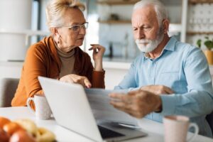 Elderly couple reviewing documents in front of a computer