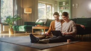 Couple Use Laptop Computer, while sitting on the living floor room of their apartment