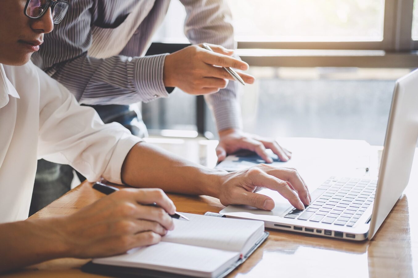 Professionals working together in front of a laptop and notebook