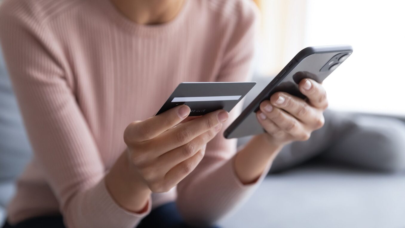 Woman holding a credit card and entering bank info in her phone