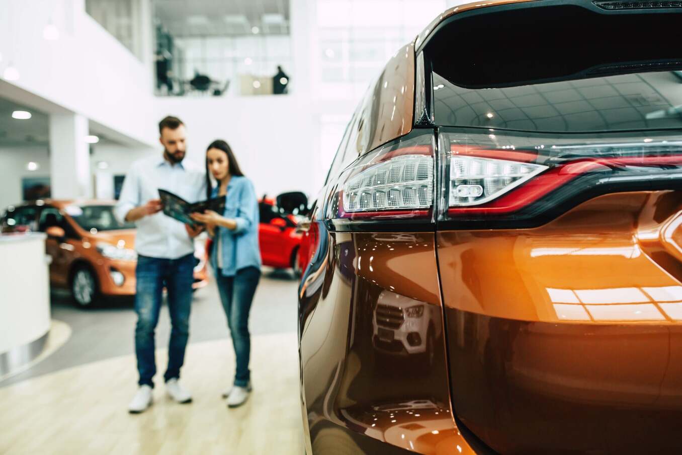 Couple looking to buy a car at a dealership. Close-up of the car headlight