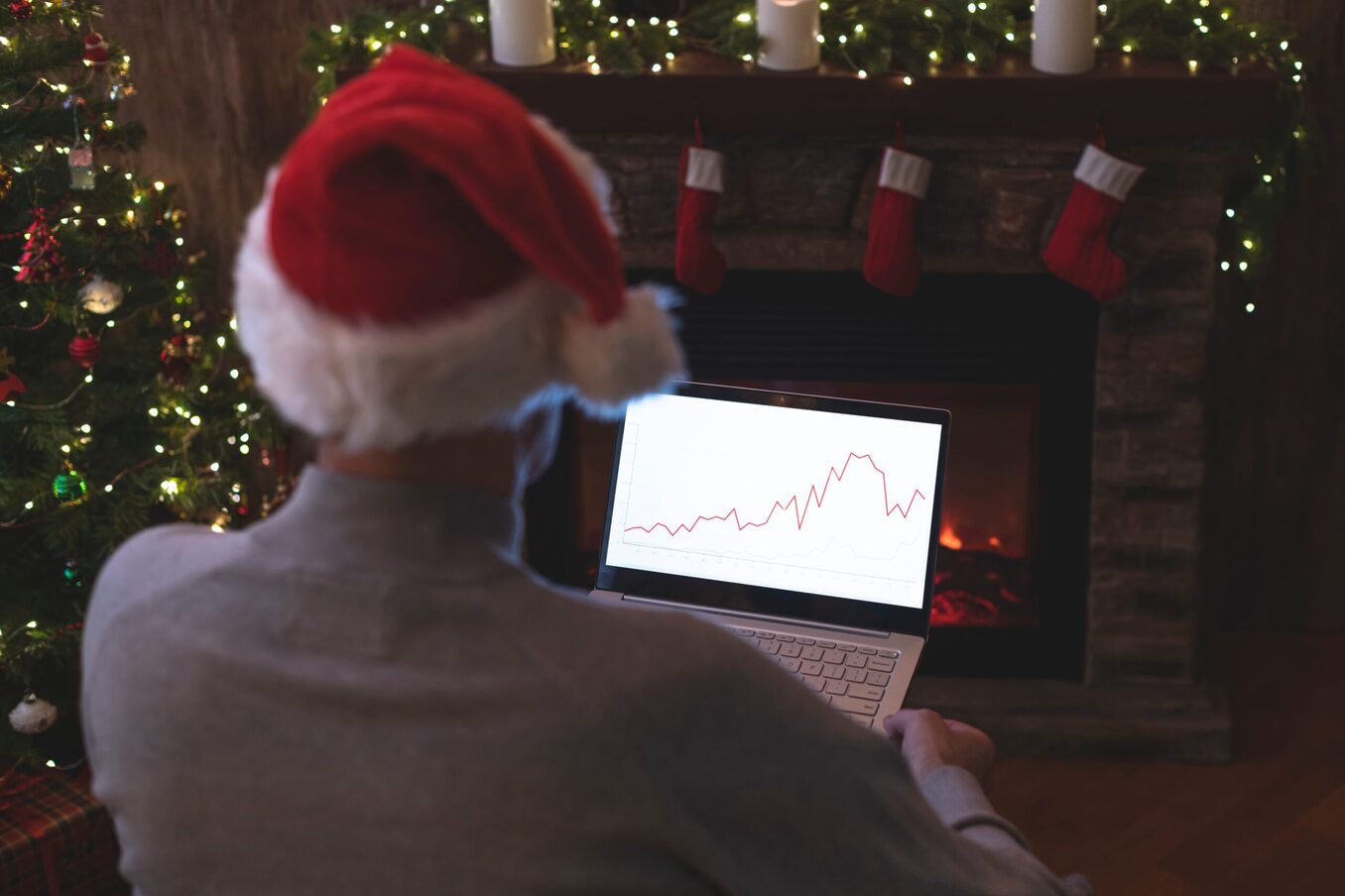 Man wearing a Santa Claus hat looking at a chart on a laptop