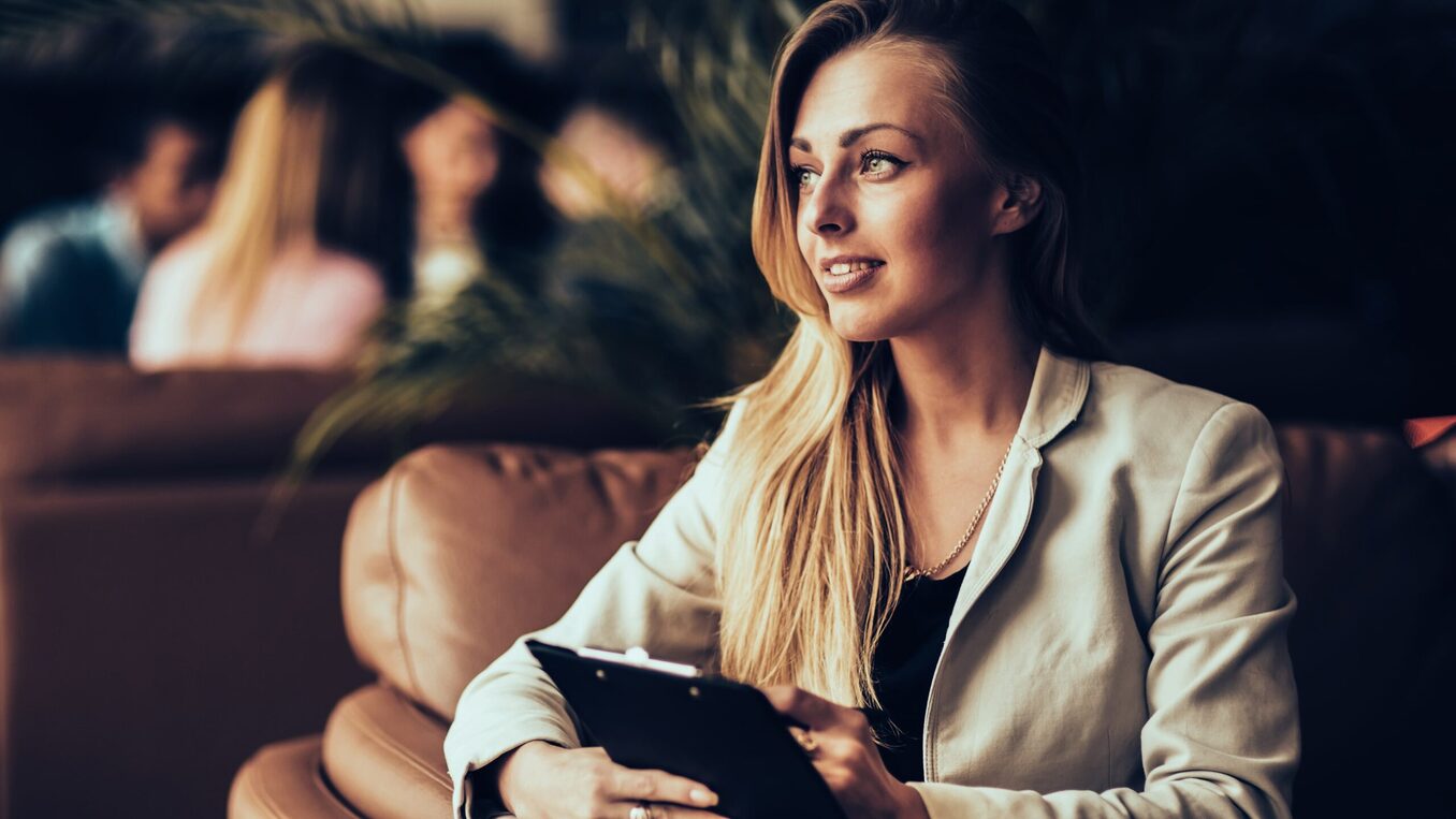 A woman smiling and looking into the distance while taking notes
