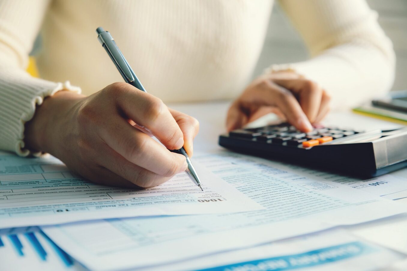 Woman filling out taxes while using a calculator on the side