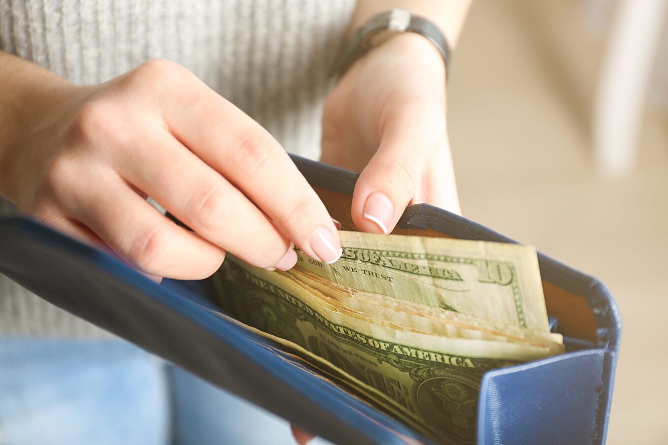 Woman taking dollar bills out from her wallet