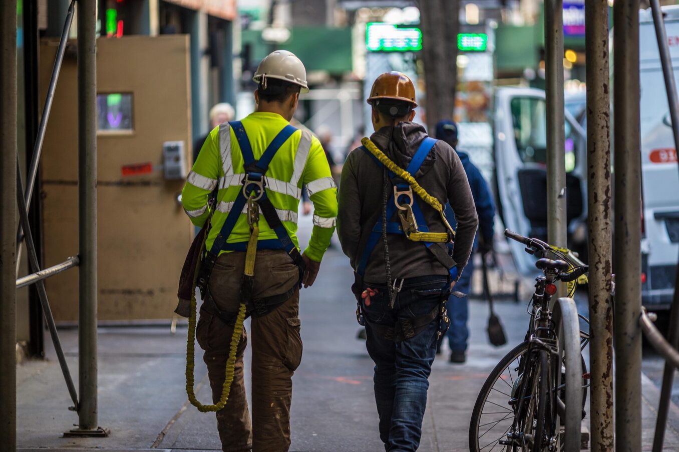 Two contractors walking on a a busy city sidewalk