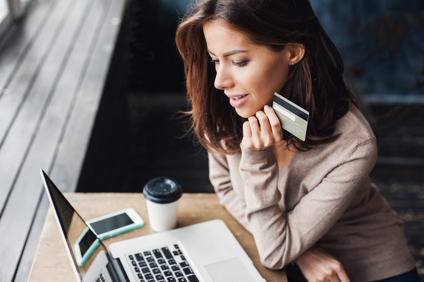 Woman holding a credit card while using a laptop