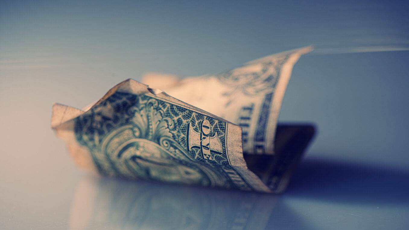 Crumpled dollar bill on reflective surface