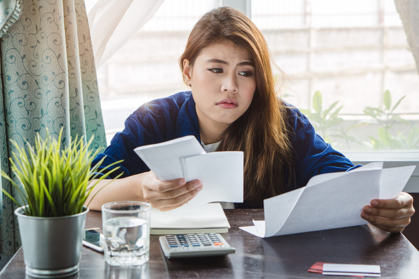stressed young asian woman trying to find money to pay credit card debt