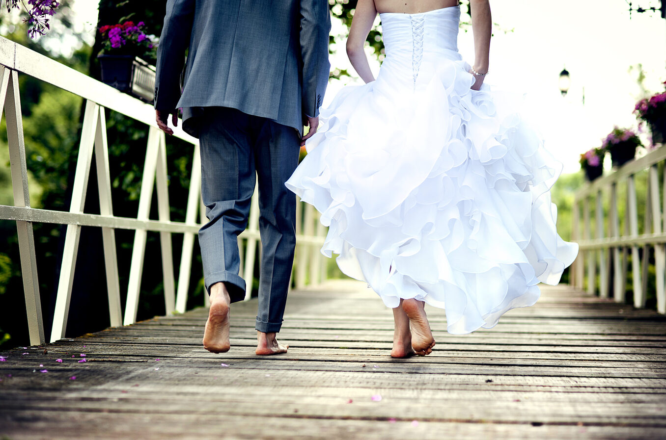 Married couple walking on bridge barefoot
