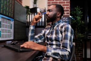 Brokerage company employee concentrated on forex stock market trend while following index marker. Investment agency data analyst thinking about risk free trading options.
