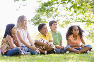 Five young friends sitting outdoors with soccer ball