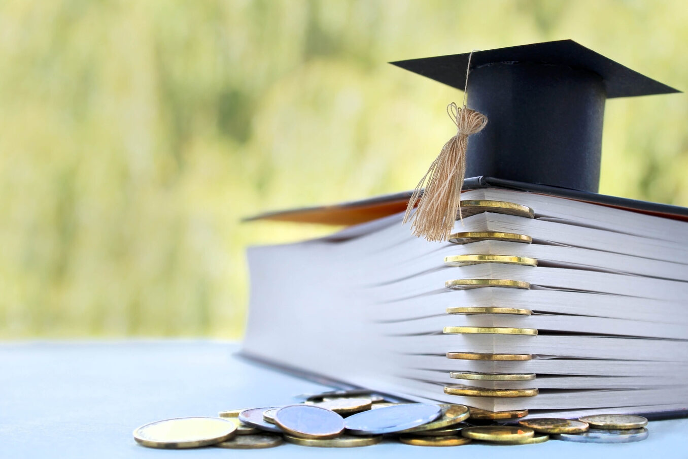 Graduation Cap for savings coins for scholarships for funding and education. Graduation microcline and gold coins and book on a green background, the concept of investment education, closure