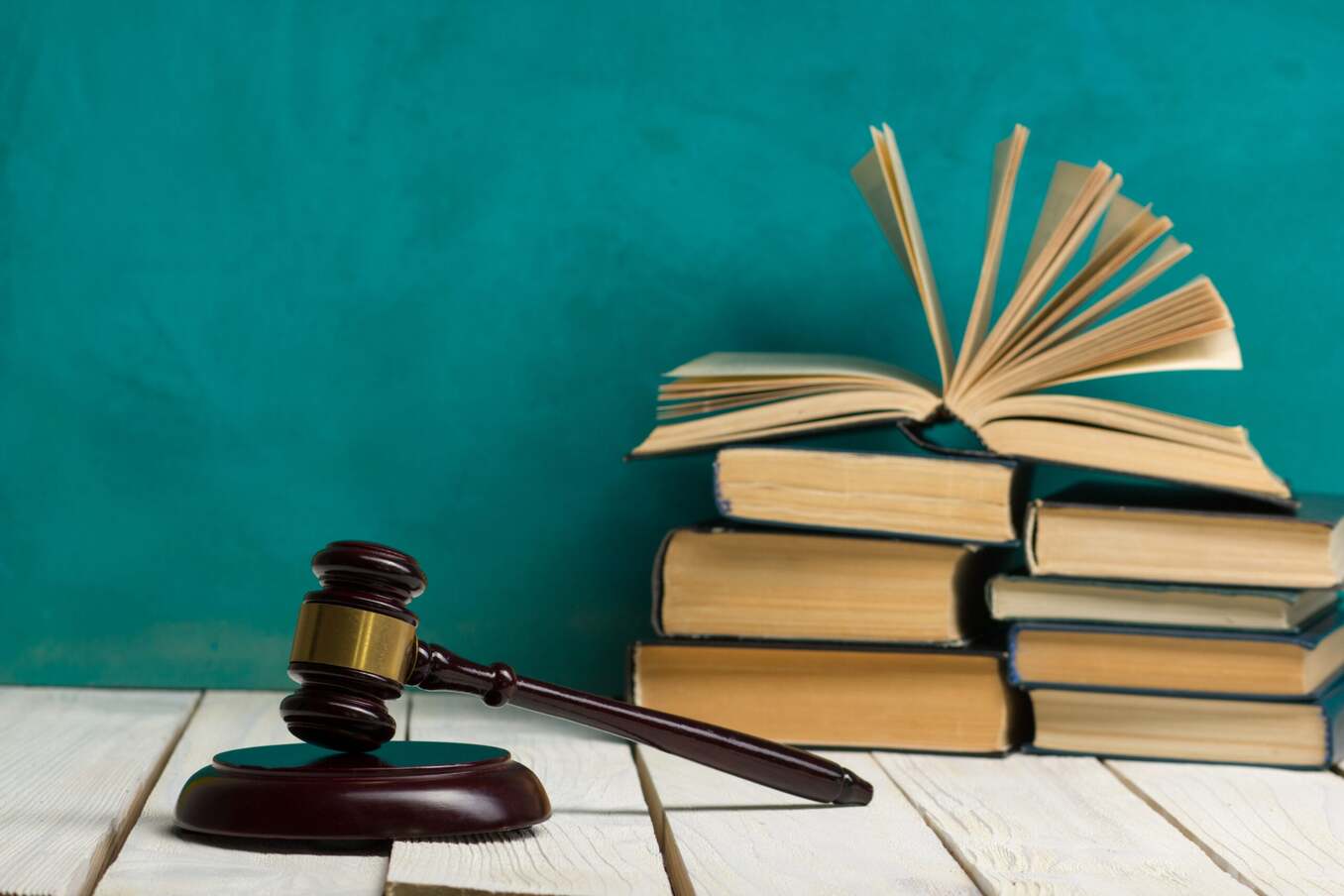 Law concept - Open law book with a wooden judges gavel on table in a courtroom or law enforcement office on blue background