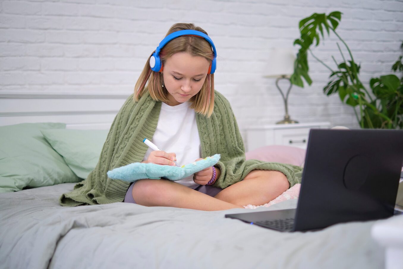 Teenage girl doing homework on the bed.