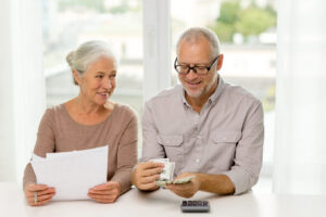 family, savings, age and people concept - smiling senior couple with papers, money and calculator at home