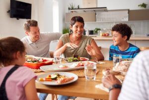 Father Serving As Multi-Generation Mixed Race Family Eat Meal Around Table At Home Together