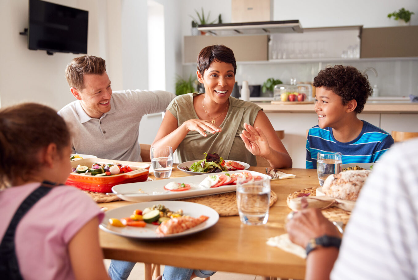 Father Serving As Multi-Generation Mixed Race Family Eat Meal Around Table At Home Together