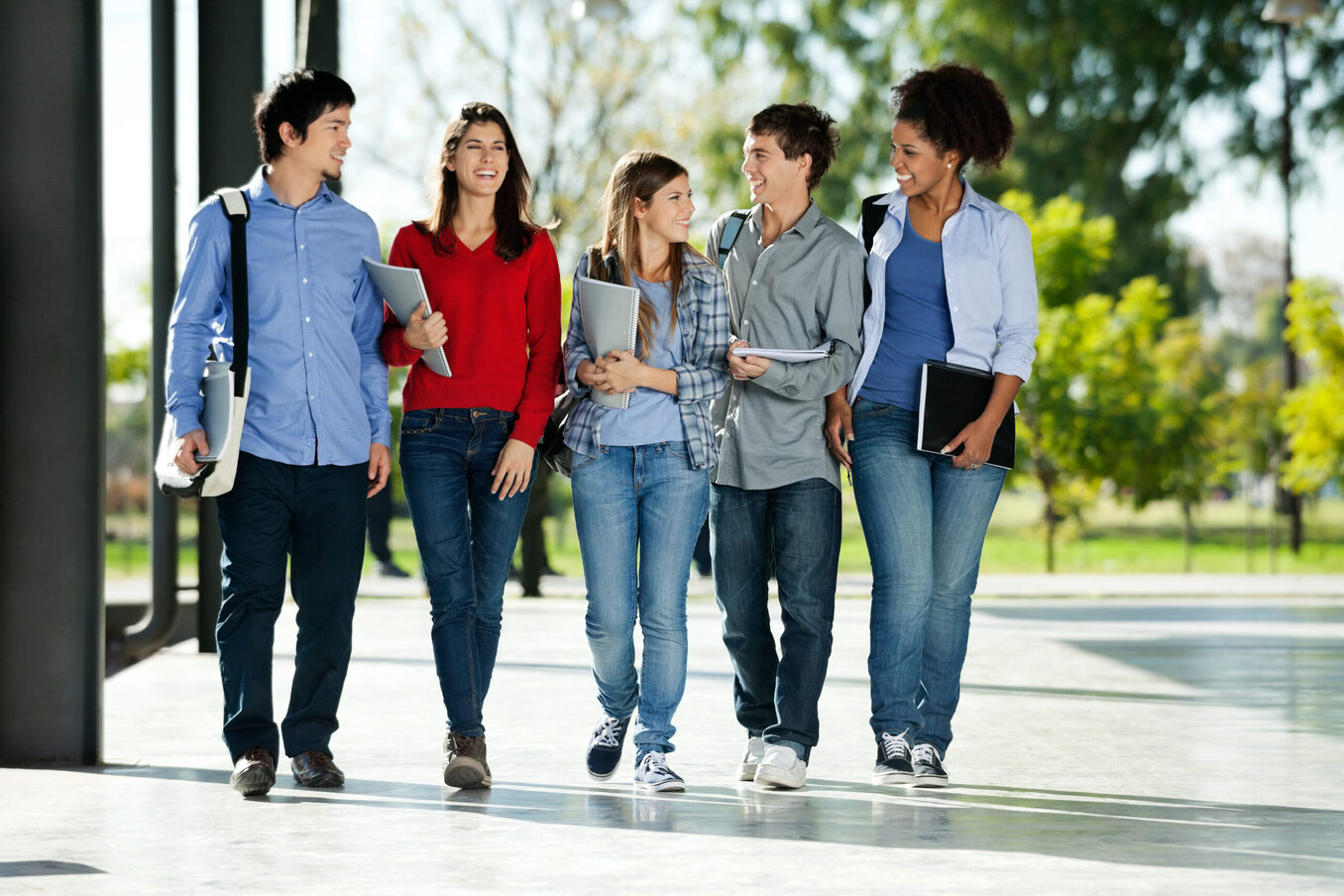 Full length of happy college students walking together on campus