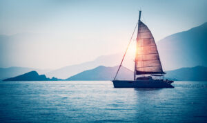Banner 3:1. Sailboat in the sea in the evening sunlight over sky background. Luxury summer adventure or active vacation concept.