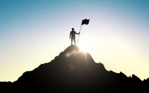 Success and achievement concept , silhouette of businessman with flag on mountain top