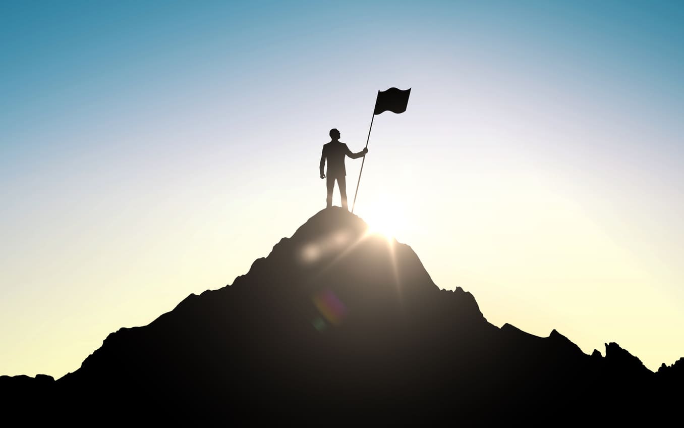 Success and achievement concept , silhouette of businessman with flag on mountain top