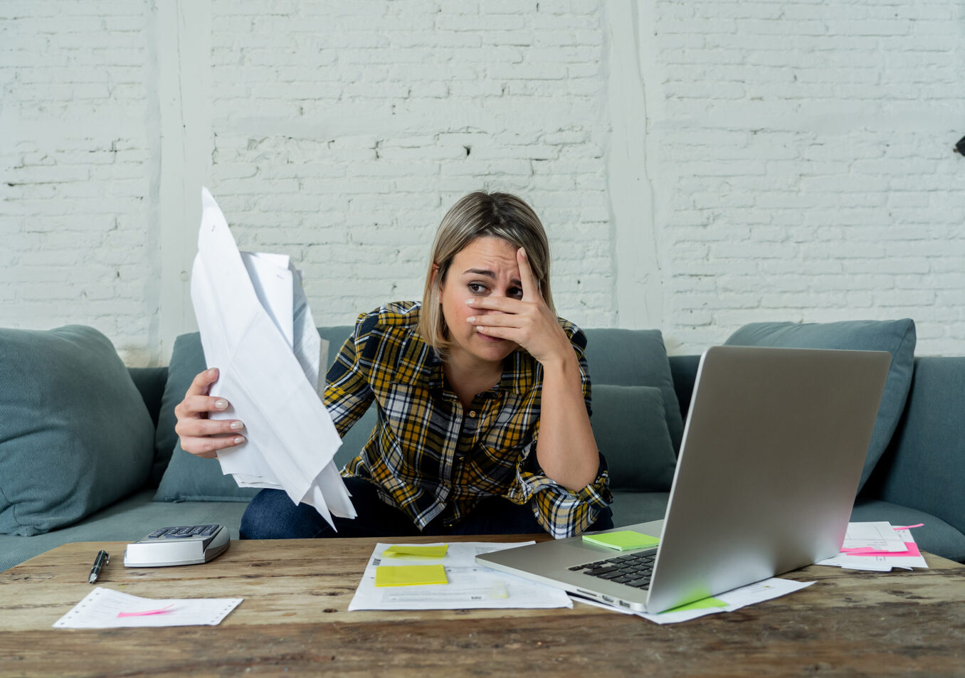 Portrait of desperate young woman feeling stressed checking online banking accounting home finances not able to pay off debts, mortgage, rent and expenses. In paying bills and financial problems.