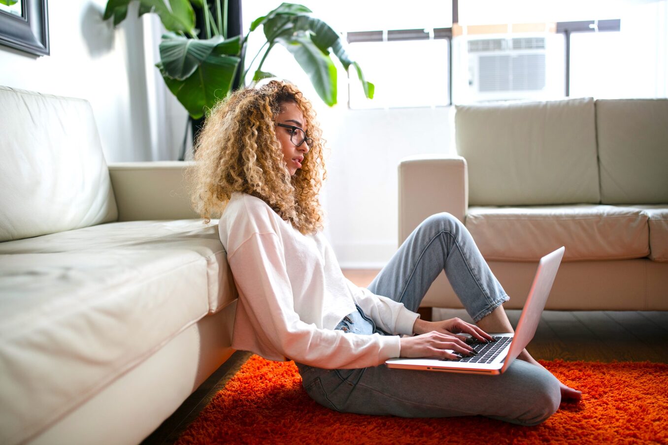Woman sitting on the floor with her laptop in a living room