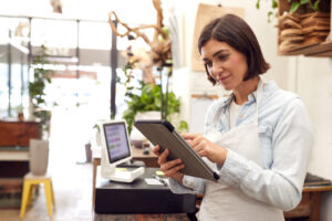 Female owner with digital tablet standing behind sales desk