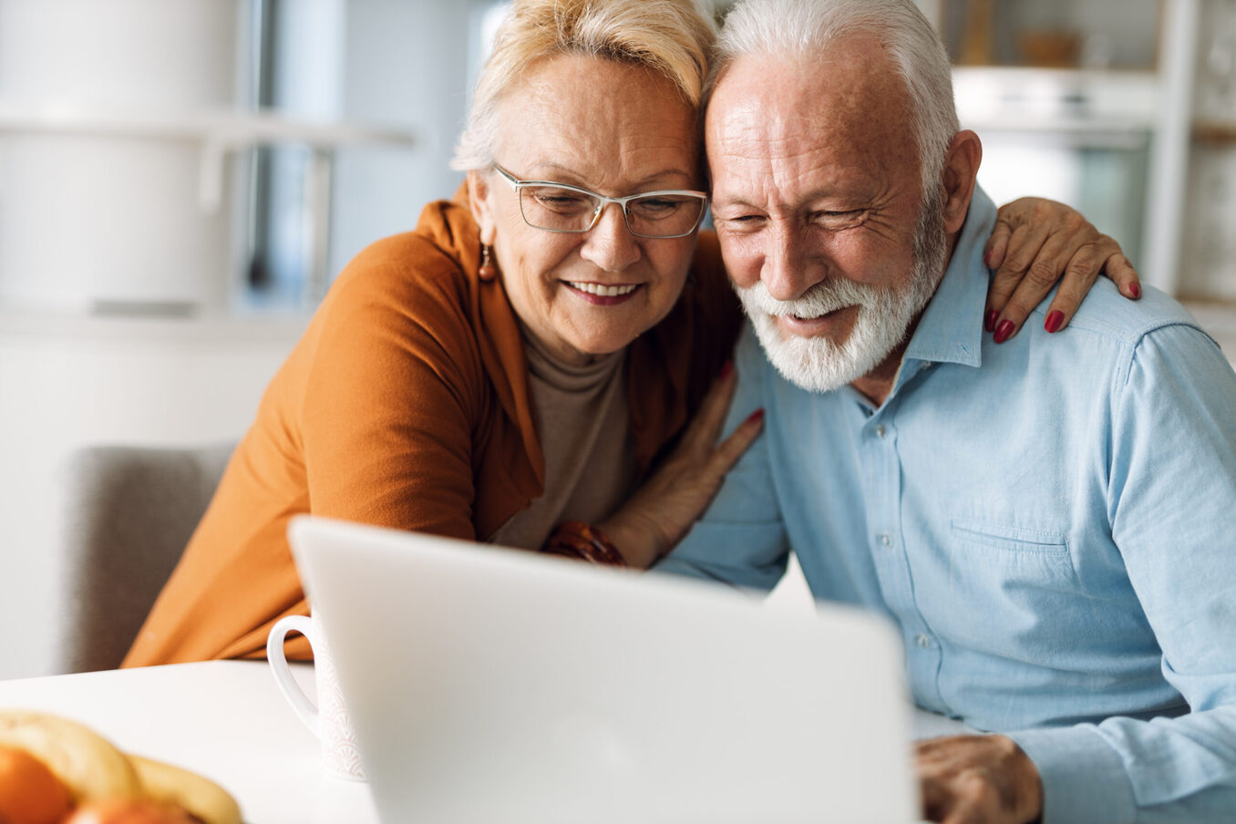 Elderly couple hugging and looking at a computer