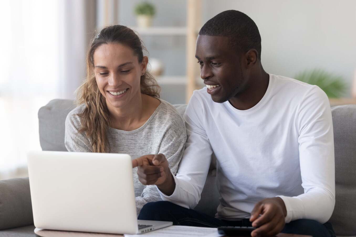 Laughing couple looking at a computer screen at home