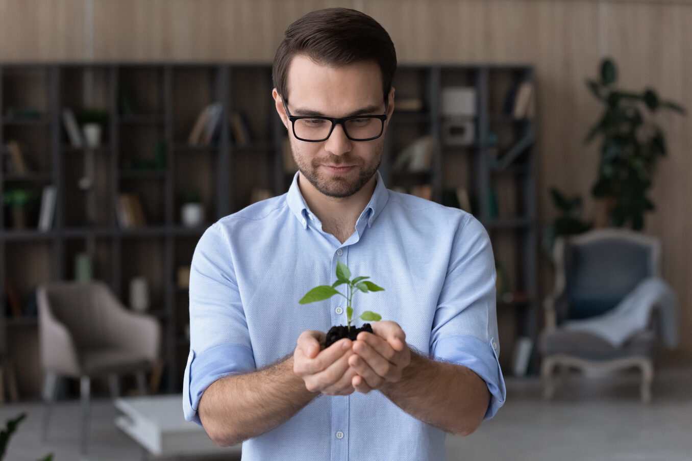 Happy young businessman holding soil green plant