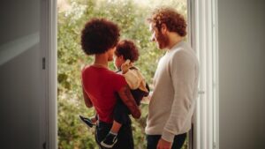 Loving Mixed Race Family Playing with Adorable Baby Boy at Modern Home, Holding Child. Cheerful Mother Nurturing a Child. Concept of Childhood, New Life, Parenthood.