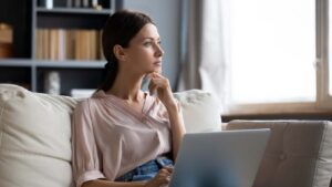 Woman contemplating in front of laptop on the couch