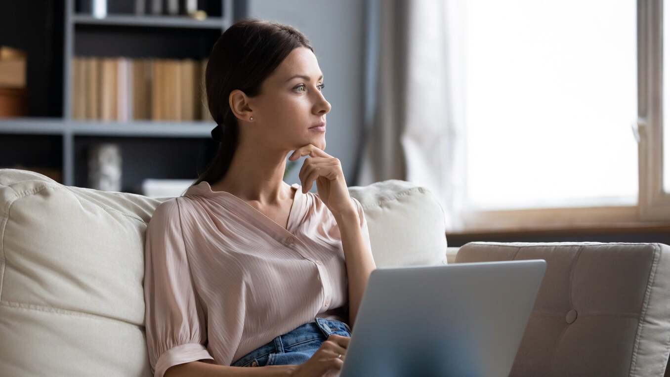 Woman contemplating in front of laptop on the couch