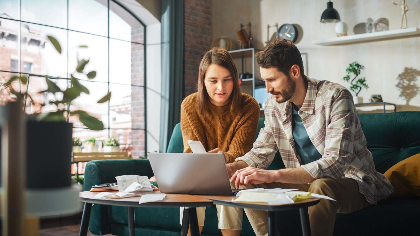 Couple looking at documents on a laptop and talking