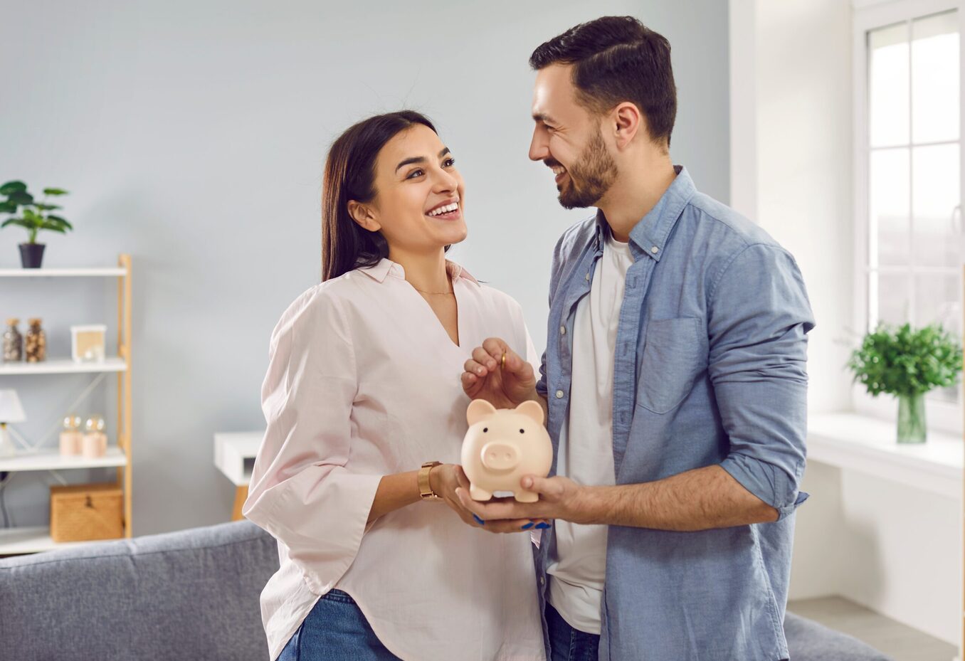 Smiling happy young family together put coins in piggy bank