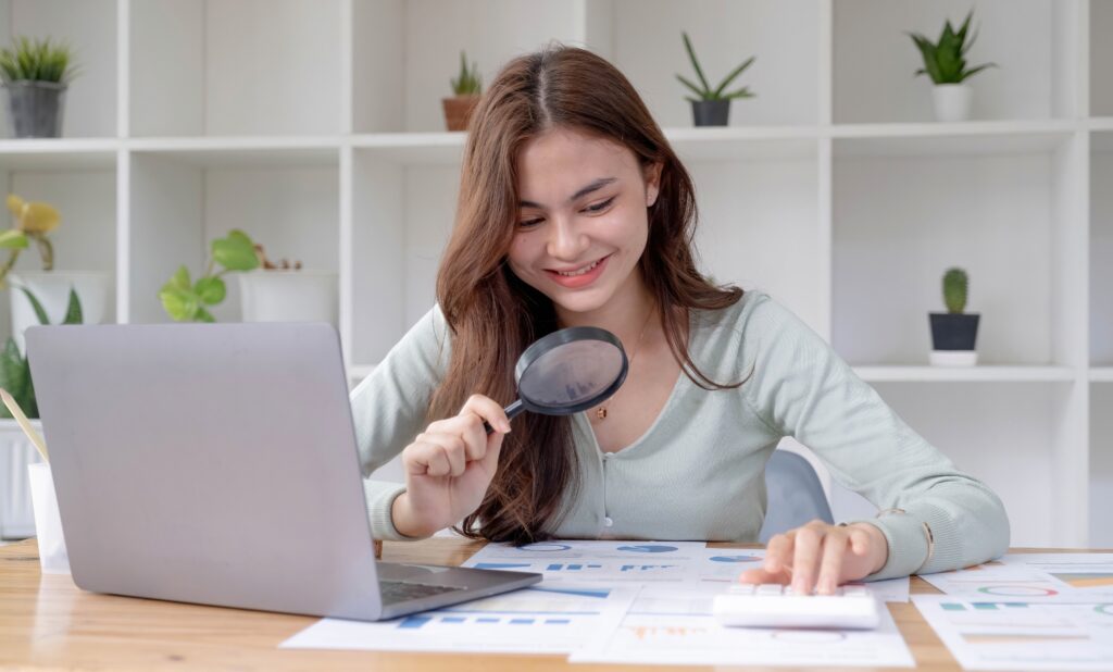 Woman with magnifying glass analyzing mutual fund expense ratios