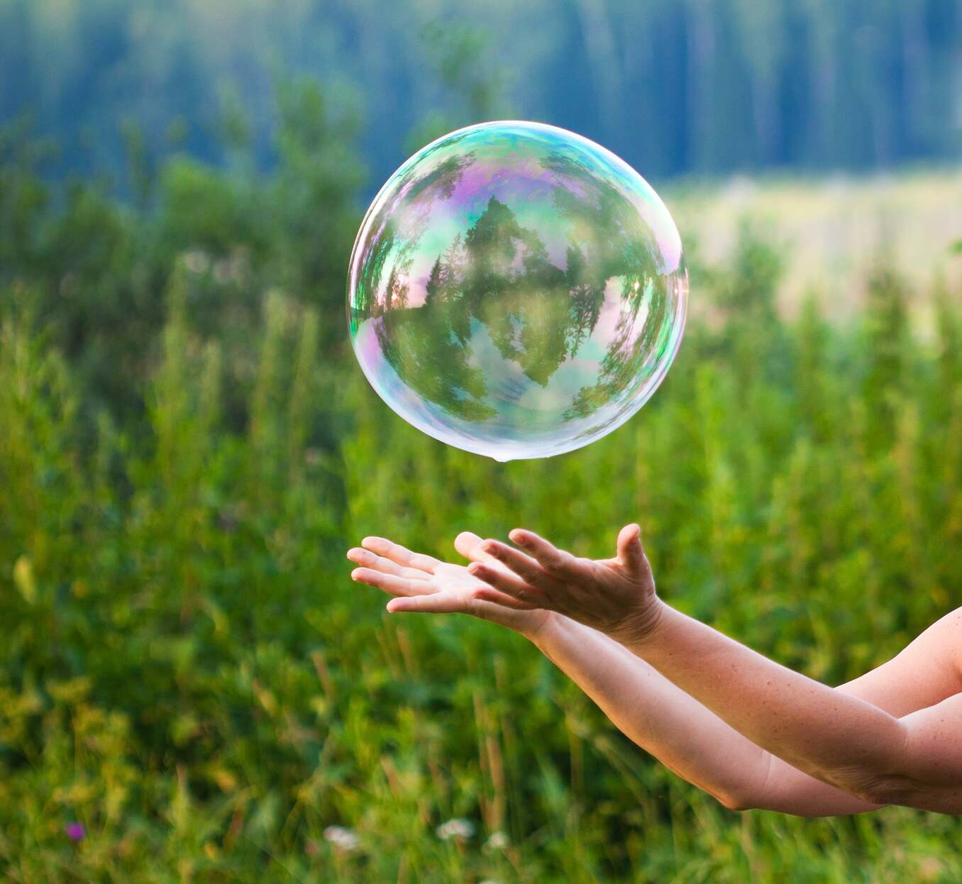 Hand catching a soap bubble