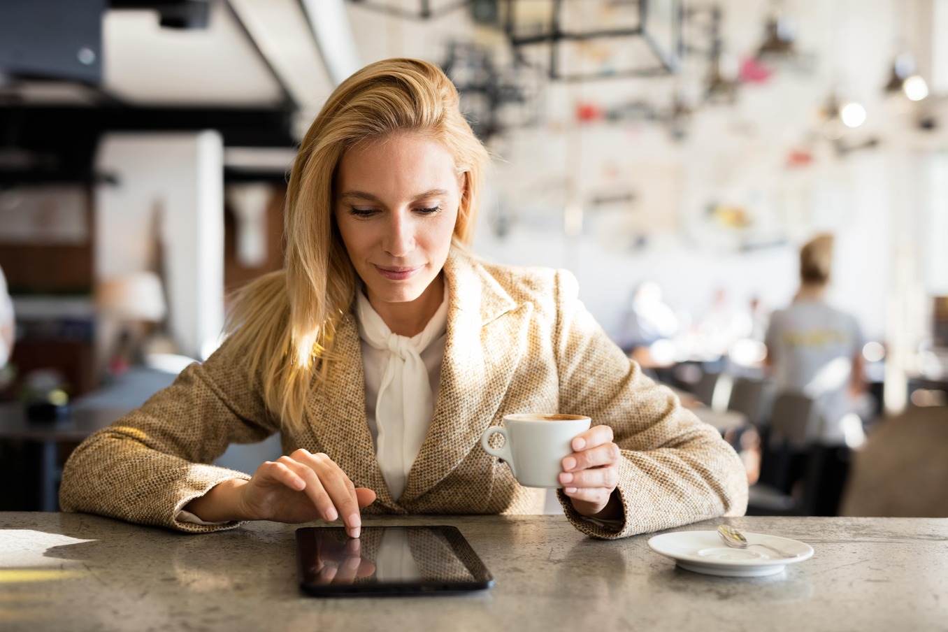 Woman in coffee shop reading from a tablet
