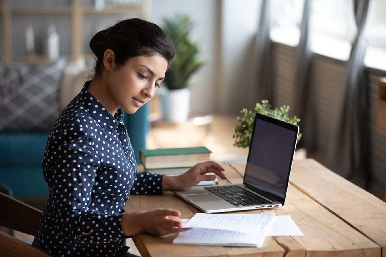 Millennial Indian girl sit at desk in living room study