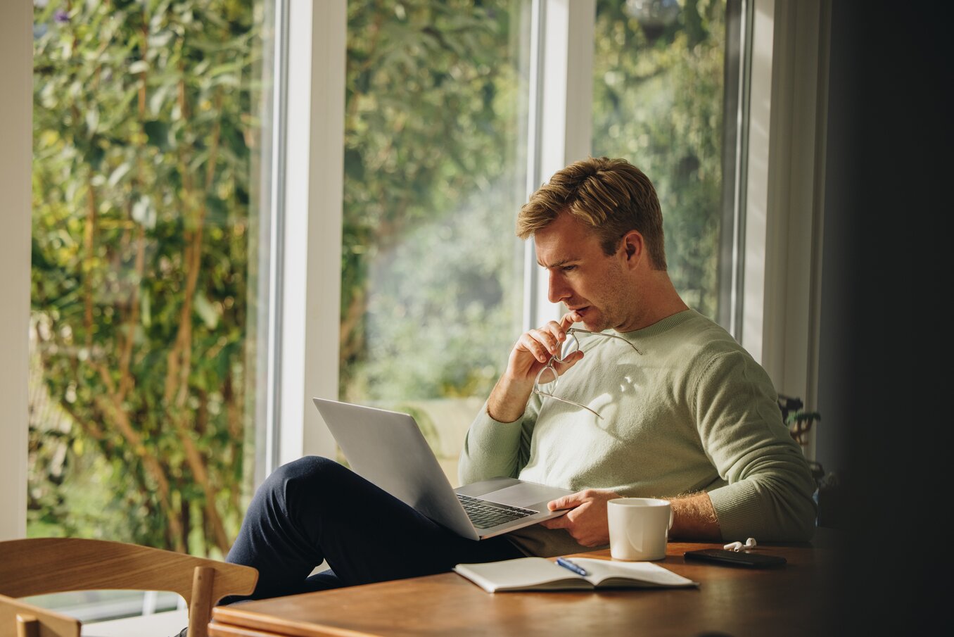 Man working on laptop and thinking. Man sitting at home looking at laptop and thinking.
