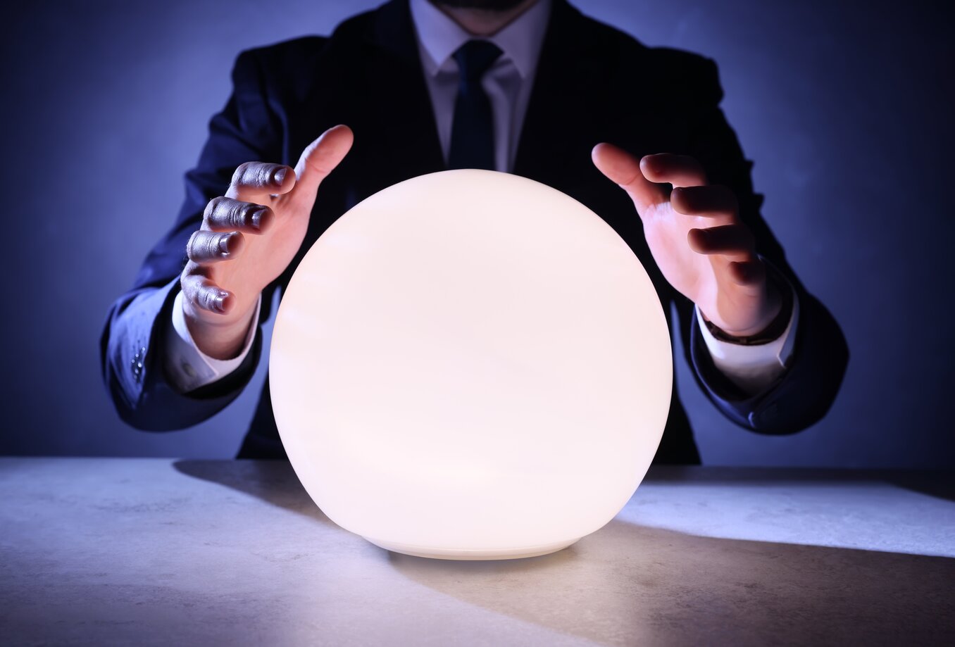 Businessman using glowing crystal ball to predict future at table, closeup